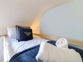 Un dormitorio con cama, almohadas, una manta y una toalla.