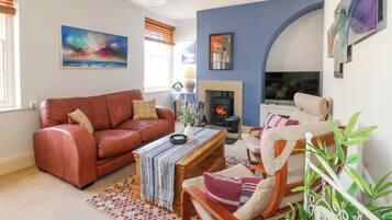 A living room with a fireplace, a sofa, a coffee table, and a TV.