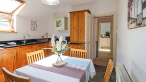 Una cocina con armarios de madera, una mesa de comedor con sillas, una lámpara colgante y una ventana con vistas.