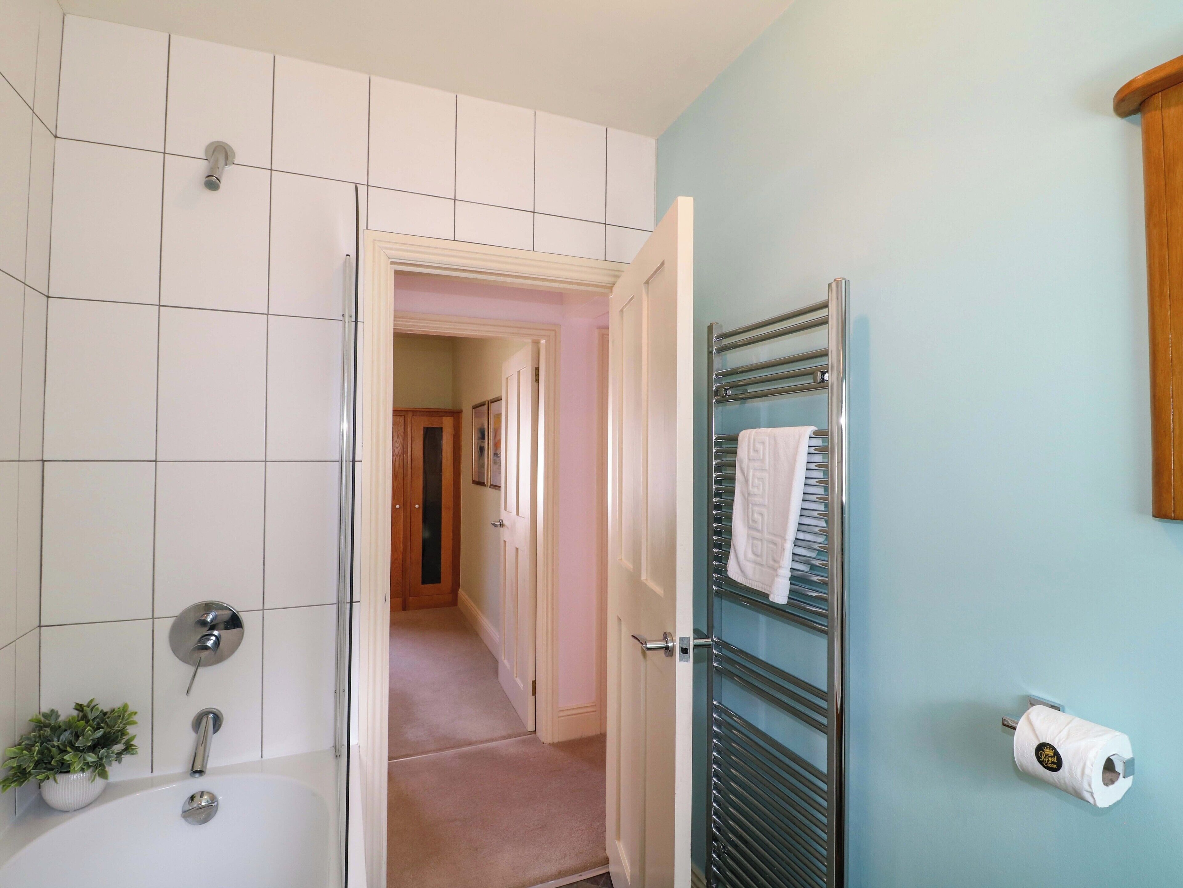 Un baño con bañera, perchero y dispensador de papel higiénico.