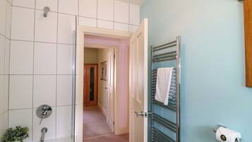 Un baño con bañera, perchero y dispensador de papel higiénico.