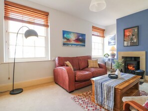 A living room with a leather sofa, a fireplace, a floor lamp, and artwork on the walls. - 2A Water Street (Bakewell)