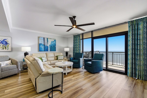 A modern living room with a sofa, chairs, a coffee table, and a ceiling fan. - South Wind 1206 - Oceanfront Condo with Amazing Views! (Myrtle Beach)