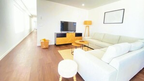 Una sala de estar moderna con un sofá, un televisor, una lámpara y una mesita.