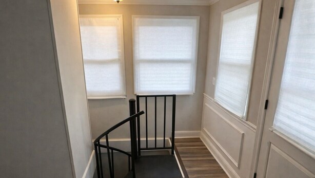 Eine Treppe mit schwarzem Geländer, Holzboden und weißen Wänden.