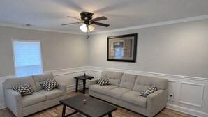 Ein Wohnzimmer mit zwei Sofas, einem Couchtisch, einem Deckenventilator und einem gerahmten Bild an der Wand.