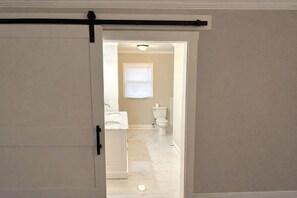A hallway leading to a bathroom with a toilet, sink, and a window. -  4-BR, 3 bath in Atlanta,  3.6 mi from MB Stadium. 8 beds 1 queen sofa sleeper. (Atlanta)