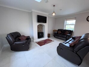 A living room with a fireplace, a flat-screen TV, and a large window.