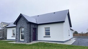 A modern two-story house with a stone facade, a dark roof, and a well-maintained lawn. - Large Modern Cottage, near the Medieval town of Athenry, Co Galway (North Athenry)