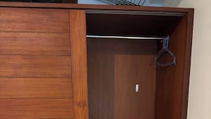 Une armoire en bois dotée d’une porte coulissante, d’une tringle et d’un petit meuble à tiroirs.
