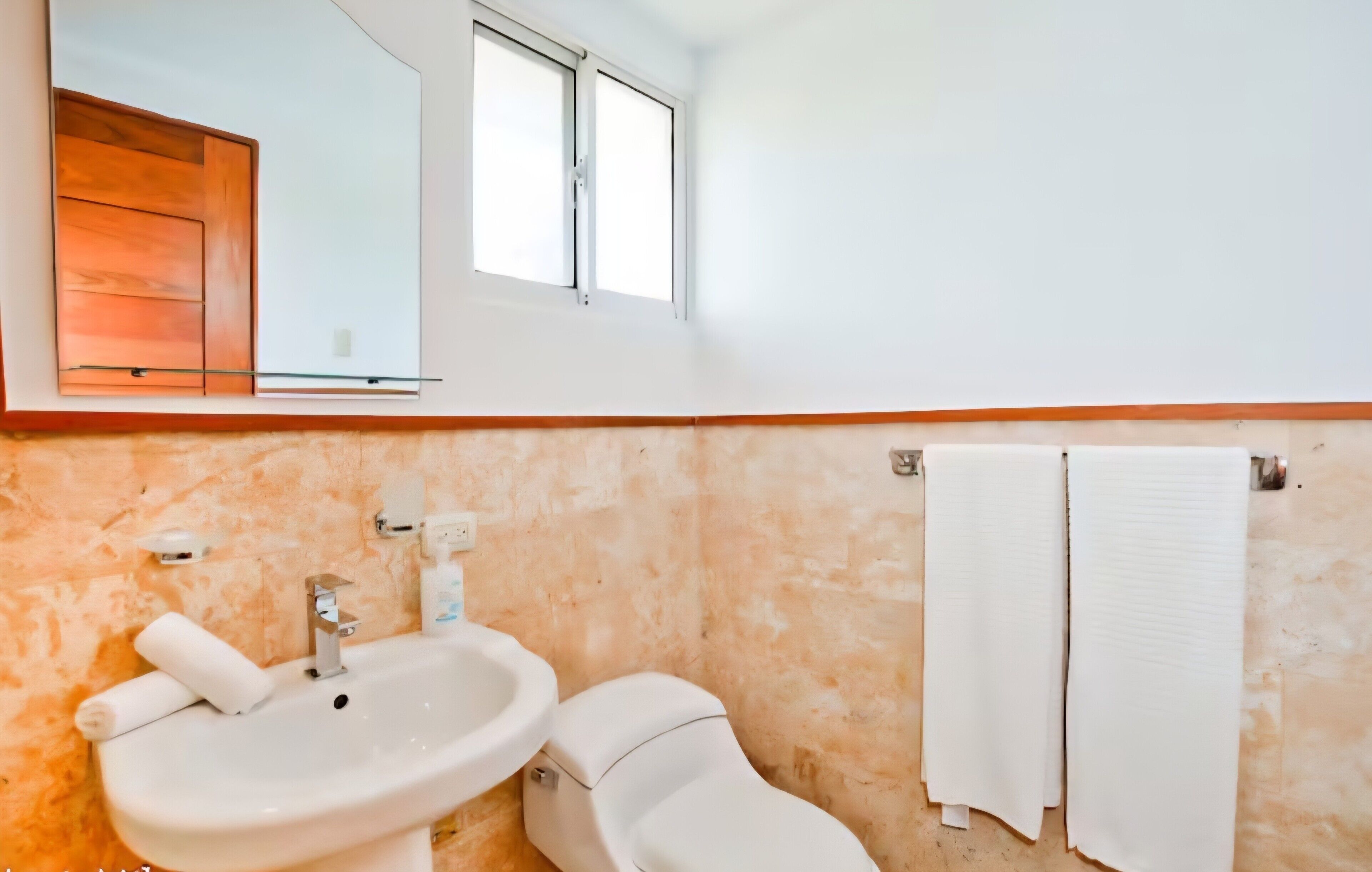 A bathroom with a sink, toilet, mirror, and towel rack.