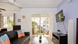 Ein Wohnzimmer mit einer Couch, einem Couchtisch, einem an der Wand montierten Fernseher und einer Glastür zum Außenbereich.