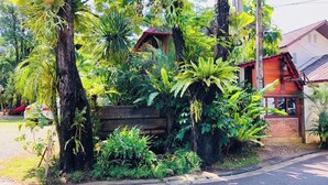 A lush garden with various tropical plants and a wooden signboard. - 403 Serene Teak Boutique Apartments (Chiang Mai)