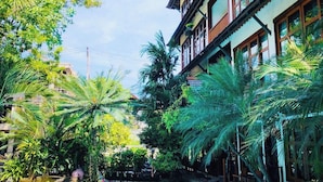 A pool surrounded by lush greenery and a multi-story building with balconies. - 403 Serene Teak Boutique Apartments (Chiang Mai)