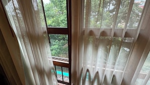 A room with a view of trees through a window with white curtains. - 403 Serene Teak Boutique Apartments (Chiang Mai)