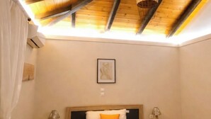A bedroom with a sloped ceiling, a bed with a blue bedspread, two bedside tables with lamps, and a framed picture on the wall.