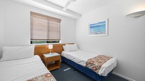 A bedroom with two beds, a nightstand, a window with blinds, a framed picture on the wall, and a ceiling light. - Mooloolaba Resort next to beach 2BR apartment (Mooloolaba)