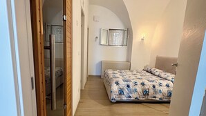 Un dormitorio con una cama, un armario, un espejo y una ventana pequeña.