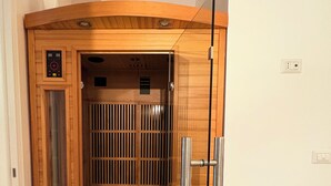 Una sauna con revestimiento de madera, un panel de control y una puerta de cristal.