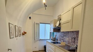 Una cocina con armarios blancos, piso de madera, alfombra estampada y ventana con vistas.