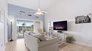 Ein Wohnzimmer mit einer Couch, einem Fernseher und einem Deckenventilator.