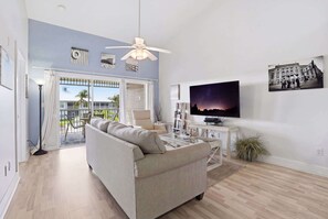 A living room with a sofa, a television, and a ceiling fan. - #123 - Lake View, Tall Ceilings W Rare Floor Plan (Naples)