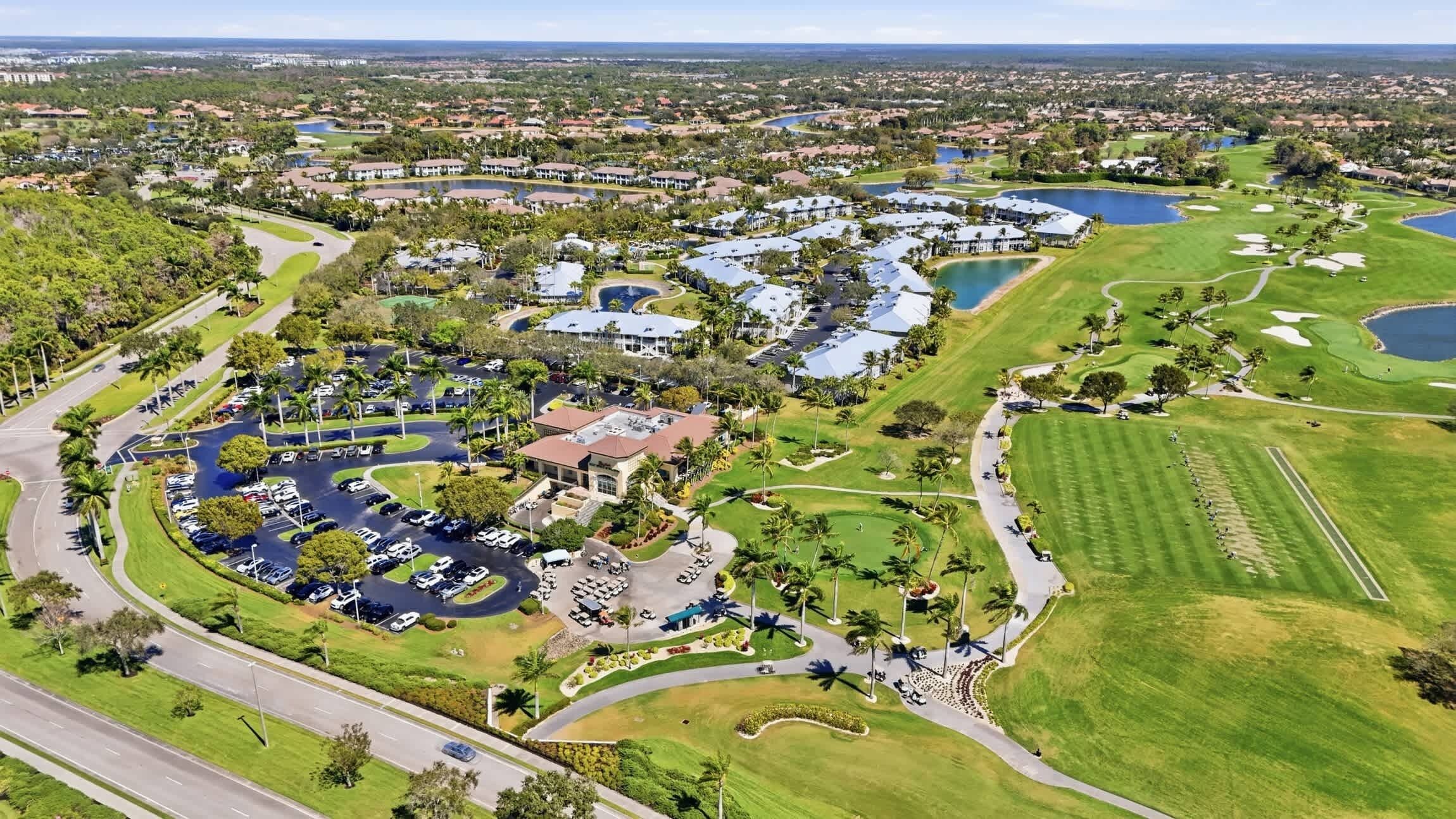 An aerial view of a golf resort with multiple buildings, a parking area, and a large golf course.