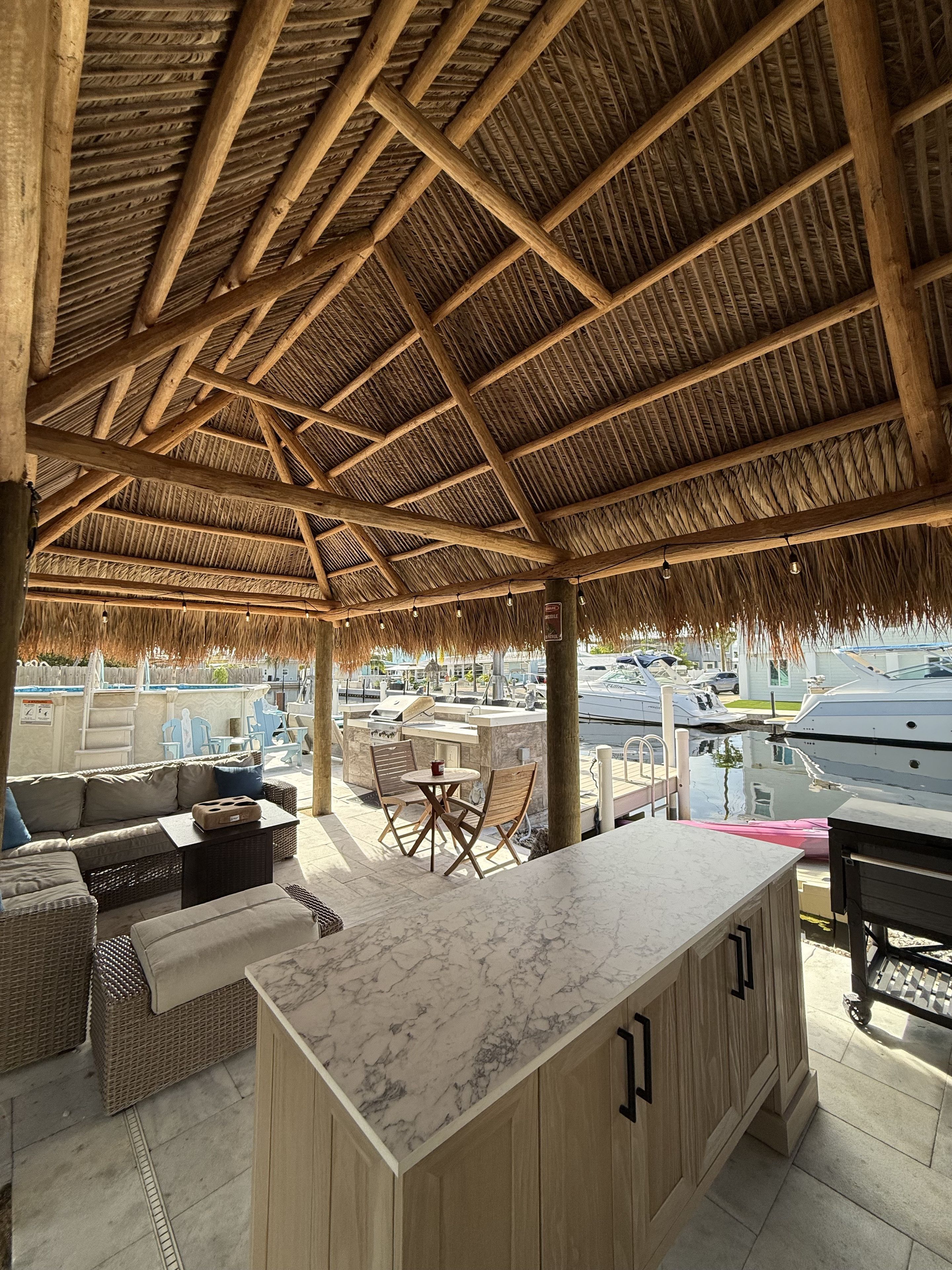 Zona relax all'aperto con copertura in legno e un bancone in marmo.