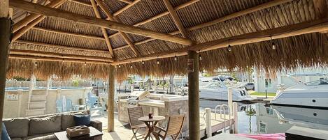 A covered outdoor seating area with a wooden ceiling and a marble bar.