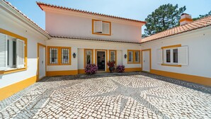 Ein Innenhof mit gefliestem Boden, ein Gebäude mit gelben Verzierungen und einer Tür.