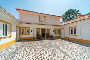 Ein Innenhof mit gefliestem Boden, ein Gebäude mit gelben Verzierungen und einer Tür.