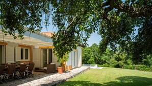 Ein Haus mit Terrasse, Sitzgelegenheiten im Freien und einem Rasen.