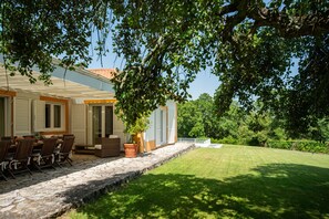 Ein Haus mit Terrasse, Sitzgelegenheiten im Freien und einem Rasen.