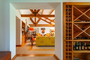 Ein Zimmer mit Holzboden, einem gelben Blumensofa, einem Weinkühlschrank und einem Bücherregal.