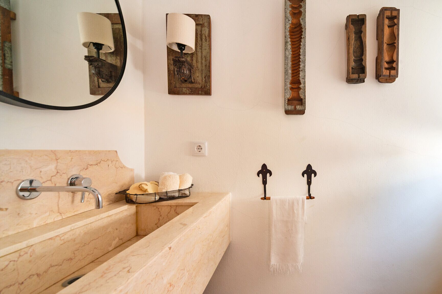 A bathroom with a marble sink, a mirror, a towel rack, and decorative wall pieces.