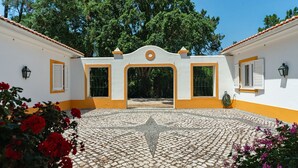 Ein Innenhof mit gefliestem Boden, einem zentralen Bogen und einem weißen Gebäude mit gelbem Zierstreifen.