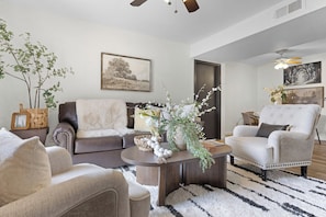 Ein Wohnzimmer mit einer Couch, Sesseln, einem Couchtisch und Zimmerpflanzen.