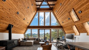 Un loft amplio con techo alto, ventanas grandes, chimenea, sofá y comedor.