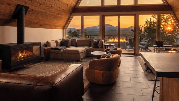 Acogedor loft con chimenea, asientos de cuero y amplias ventanas con vistas a la montaña.