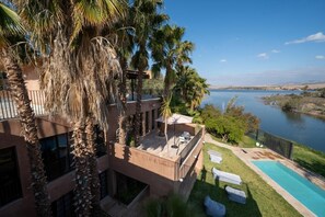 Ein modernes Gebäude mit Pool, Palmen und Blick auf ein Gewässer.