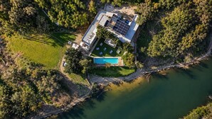 An aerial view of a house with a swimming pool, surrounded by trees and a body of water. - The House of Designers by BCKART GALLERY (Lalla Takarkoust)