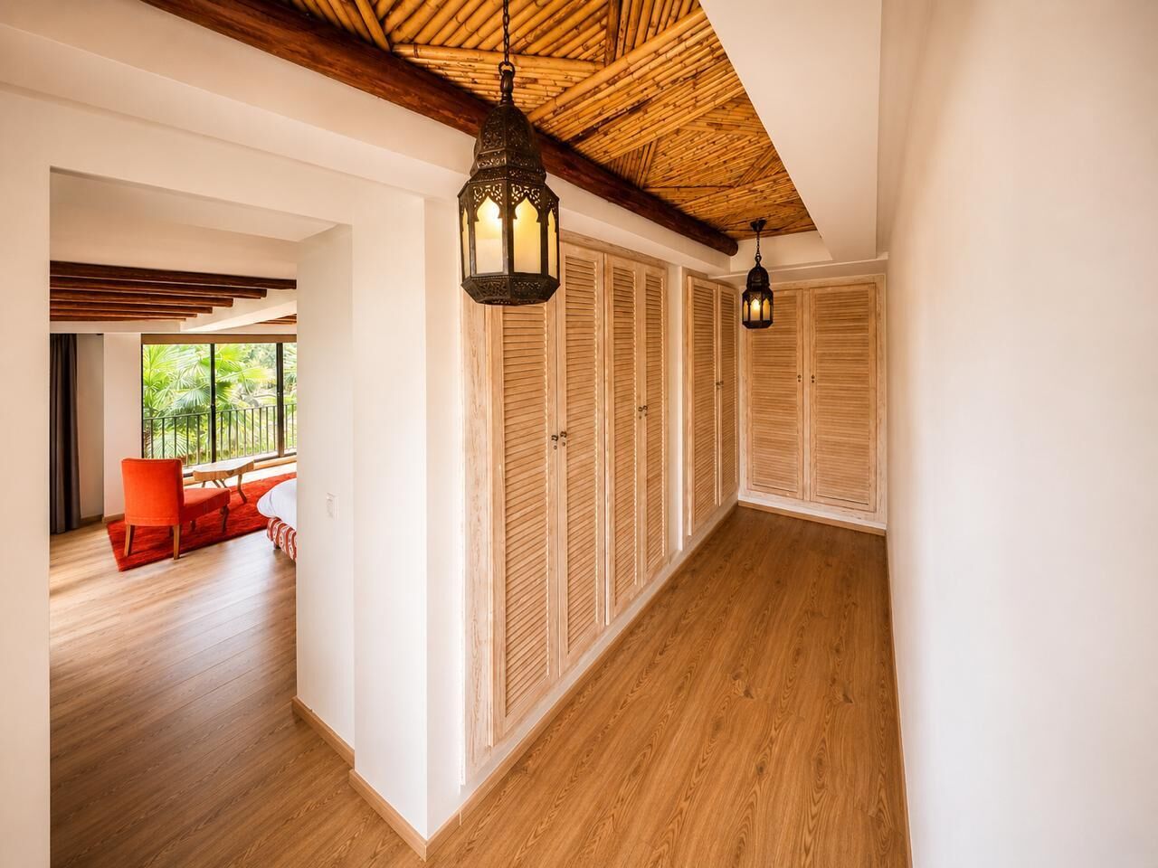 Un pasillo de hotel con piso de madera, una silla roja y un banco.