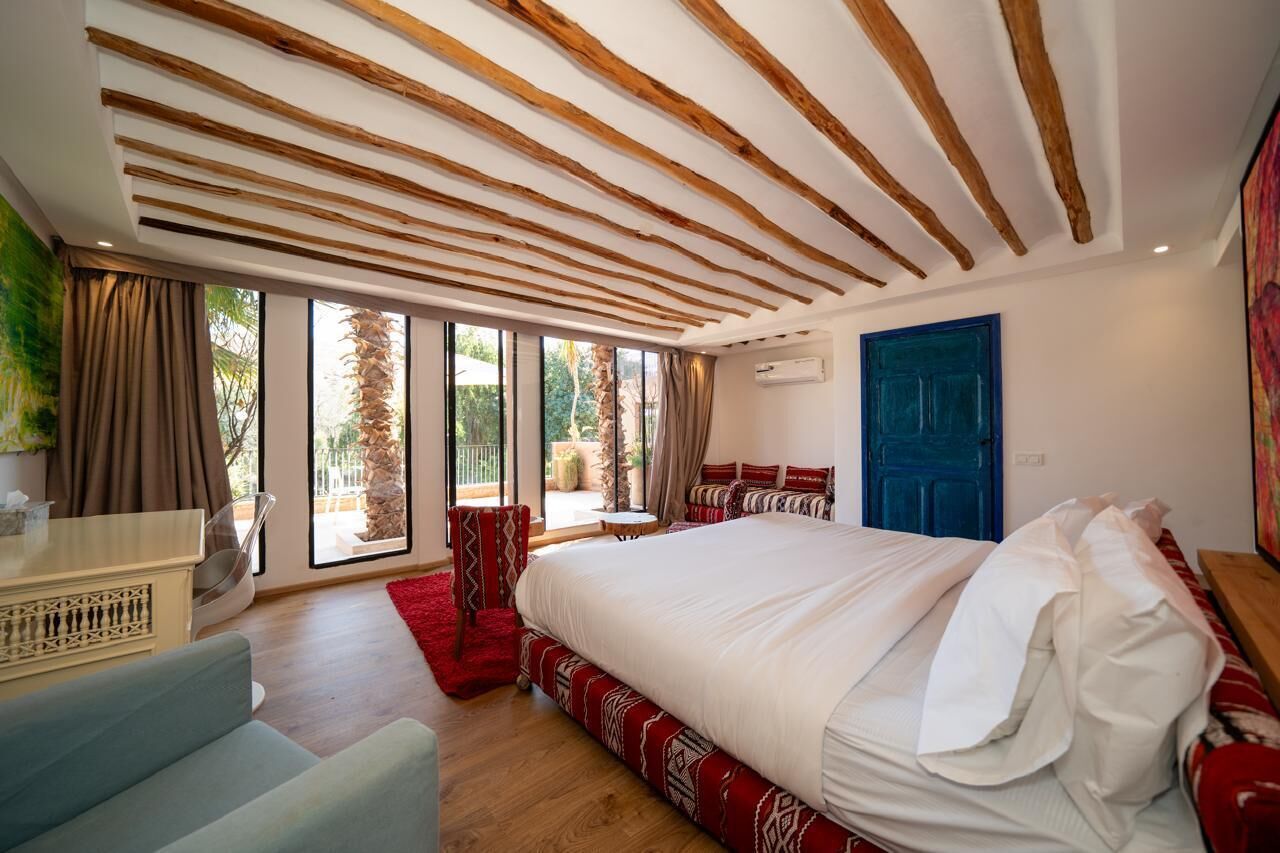 Un dormitorio con una cama grande, un escritorio, una silla y vistas al exterior.