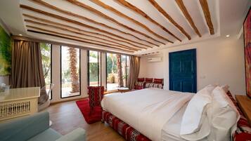 Un dormitorio con una cama grande, un escritorio, una silla y vistas al exterior.