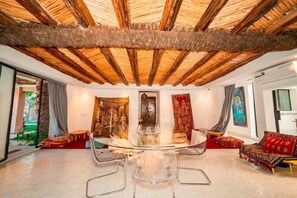 A spacious room with a glass table surrounded by chairs, a red sofa, and a large painting on the wall. - The House of Designers by BCKART GALLERY (Lalla Takarkoust)