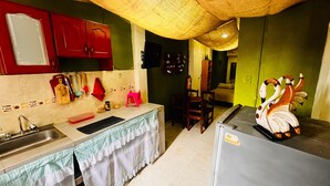 A kitchen with a sink, red cabinets, a refrigerator, and a dining area with chairs. - Apartahotel El Progreso (Armenia)