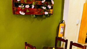 A dining area with a wooden table and chairs, a green wall, and a fire extinguisher mounted on the wall. - Apartahotel El Progreso (Armenia)