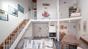 A multi-level living space with a staircase, a dining area, and a loft bedroom. - La Proue – Duplex Apartment with Sea View in Arzon, Sleeps 8 (Arzon)