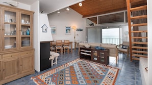 A spacious living area with a wooden cabinet, a fireplace, a sofa, a coffee table, and a patterned rug. - La Proue – Duplex Apartment with Sea View in Arzon, Sleeps 8 (Arzon)