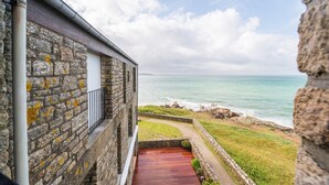 A stone building with a wooden deck overlooking a coastal view. - La Proue – Duplex Apartment with Sea View in Arzon, Sleeps 8 (Arzon)